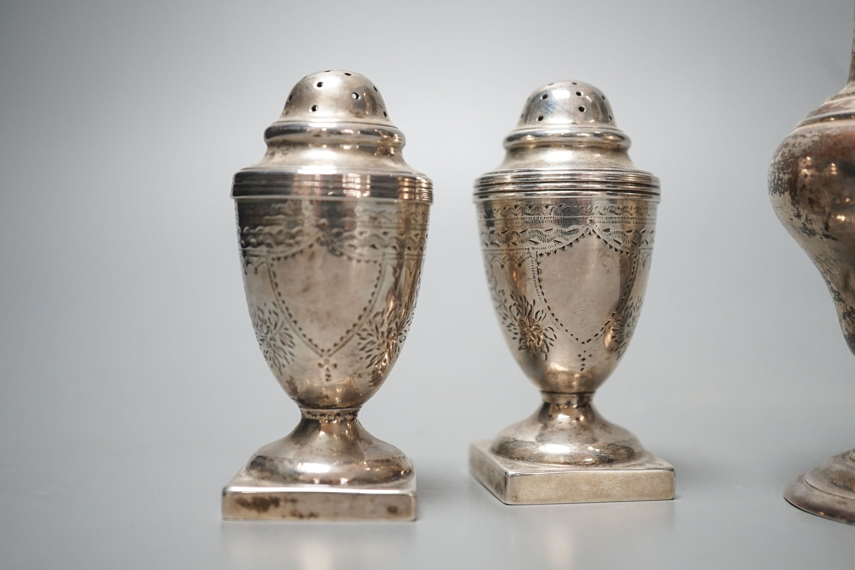 A late Victorian silver sugar caster, Charles Stuart Harris, London, 1899, 17cm and two silver early 20th century silver pepperettes, 7.5oz.